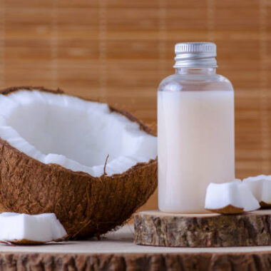 Cosmetic bottle and fresh coconut for skincare, natural brown background